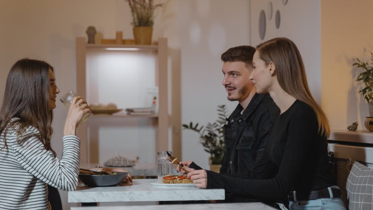A group of three friends enjoying a meal at a stylish indoor setting, capturing a moment of conversation and camaraderie.